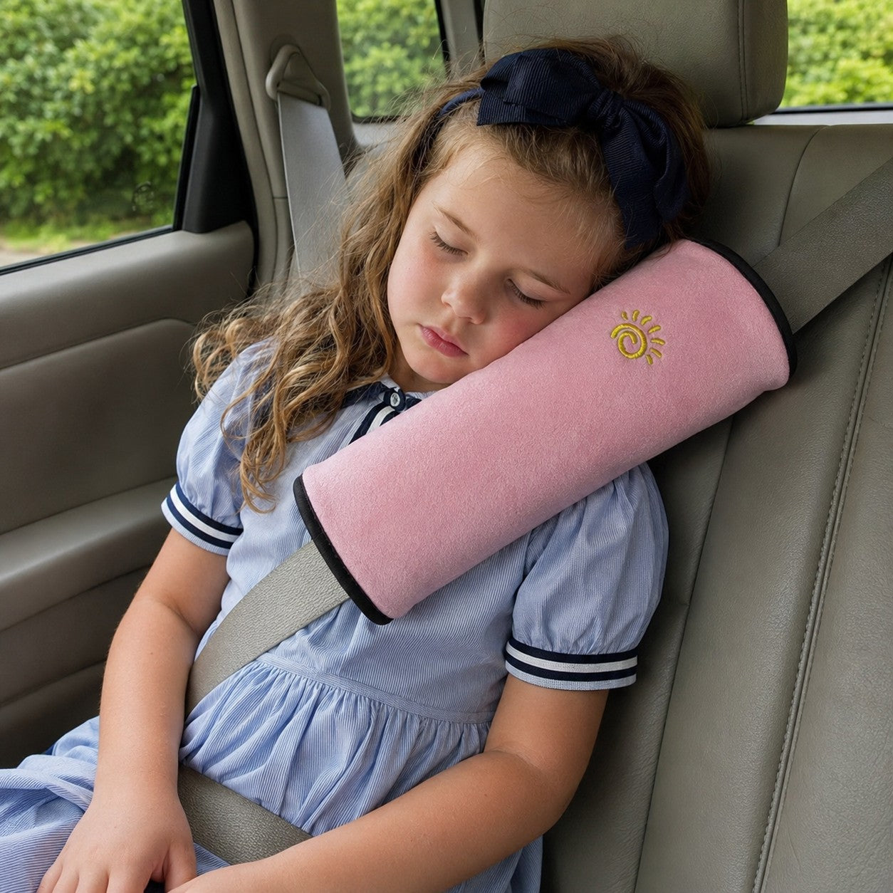 Child resting against the pink SnugBelt seat-belt pillow in the car