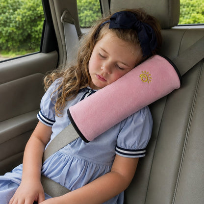 Child resting against the pink SnugBelt seat-belt pillow in the car